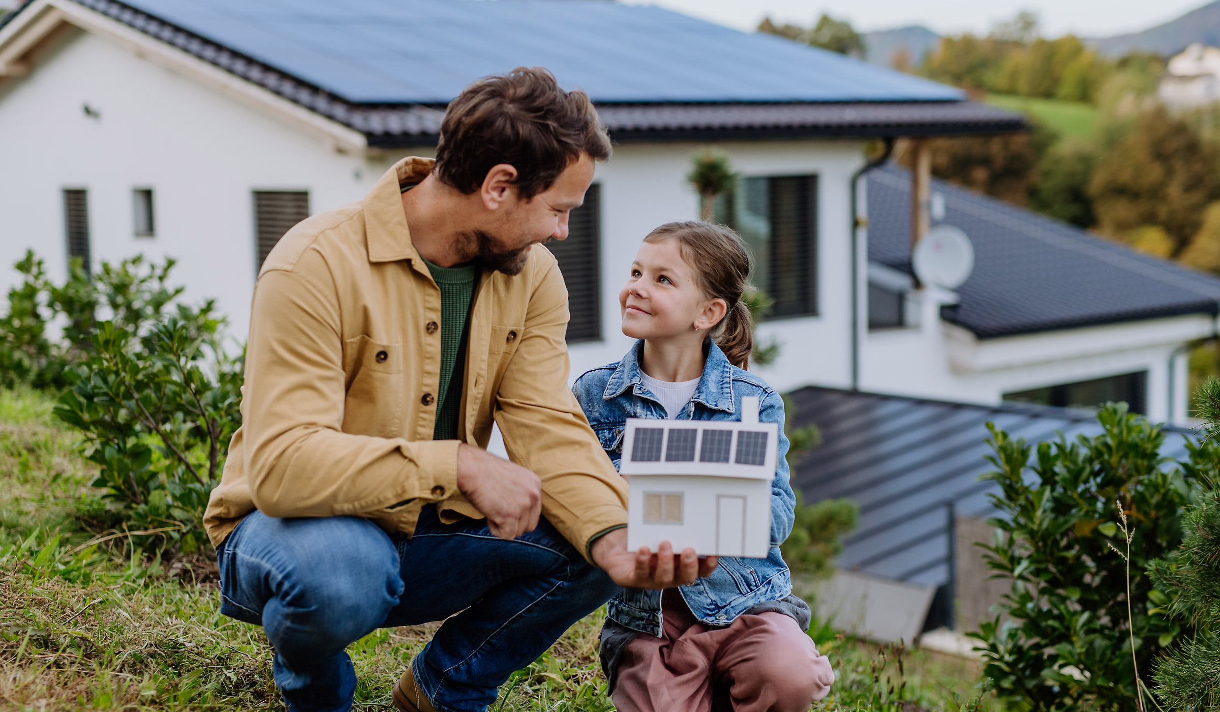 Vater zeigt Tochter Solartechnik vor dem Haus
